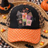 Whimsical patchwork haunted house DTF transfer with gingham, leopard, floral, and polka dot fabric-style panels, blanket-stitch edges, bats, and a purple crescent moon Shown on a black front panel, orange polka dot bill, leopard mesh back trucker hat.