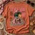 Mallard Magazine Y2K Edition DTF transfer featuring a glam mallard duck in pink camo hat, leopard sunglasses, pearls and gold chains styled as a retro magazine cover Shown on a Terracotta t-shirt.