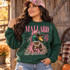 Mallard Magazine Y2K Edition DTF transfer featuring a glam mallard duck in pink camo hat, leopard sunglasses, pearls and gold chains styled as a retro magazine cover Shown on a Irish Green crewneck sweatshirt.