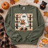 Friendly ghost DTF transfer holding a jack-o-lantern trick-or-treat bag and wearing sneakers, with checkered background and vertical TRICK TREAT lettering Shown on a Military Green crewneck sweatshirt.