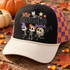 Zero Amucks Given Halloween DTF transfer with three dancing skeleton girls with colorful hair, a skeleton cat, and stars Shown on a black front panel with cream bill and orange-purple checkered mesh trucker hat.