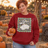 Friendly ghost dog with bat-like ears and red collar DTF transfer on a checkered background with gold stars in a scalloped frame Shown on a Cardinal Red crewneck sweatshirt.