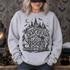 Mysterious & Spooky gothic Victorian mansion DTF transfer with crescent moon, bats, and wrought-iron gate in black ink illustration style Shown on a Sport Grey crewneck sweatshirt.
