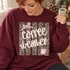 Coffee Weather DTF transfer with cream brush-script lettering over a distressed leopard print background, pink bow, and pink steaming coffee mug Shown on a Maroon crewneck sweatshirt.