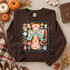 Give Thanks to the Lord Psalm 136:1 fall DTF transfer with pumpkin plaid cross, teal ribbon bow, and pink, orange, and blue florals Shown on a Dark Chocolate crewneck sweatshirt.