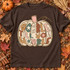 Gobble Till You Wobble DTF transfer with patchwork pumpkin design, bubble letters in fall-toned patterns, pink stem, and gold curly vine Shown on a Espresso t-shirt.