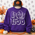 Hey Boo DTF transfer with chunky white bubble letters and a friendly waving ghost character peeking through the lettering Shown on a Purple crewneck sweatshirt.
