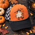 Cute ghost DTF transfer wearing a leopard print beanie and bow, holding a pink drink and leopard print jack-o'-lantern bucket, surrounded by bats and flowers on a checkered floor Shown on a burnt orange front panel with black pre-curved bill, black rope, black-and-white checkered mesh back trucker hat.