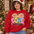 Love Came Down Luke 2:11 Christmas DTF transfer with colorful patterned block letters, baby Jesus in a manger inside the O, and a rainbow ribbon bow with starburst Shown on a Cardinal Red crewneck sweatshirt.
