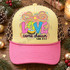 Love Came Down Luke 2:11 Christmas DTF transfer with colorful patterned block letters, baby Jesus in a manger inside the O, and a rainbow ribbon bow with starburst Shown on a Butter yellow front panel, pink bill, leopard mesh back trucker hat.