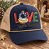 LOVE came down nativity DTF transfer with baby Jesus in a manger inside patterned block letters and Luke 2:11 scripture script Shown on a navy front panel with tan mesh back and a gold rope trucker hat.