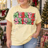 Merry & Bright bubble-letter Christmas DTF transfer in pink, green, and red with glowing string lights Shown on a Butter t-shirt.