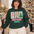 Nutcracker Season DTF transfer with yarn-embroidered-look ballerina, crowned nutcracker soldier, and Christmas tree patches on candy-striped backgrounds and chenille lettering Shown on a Forest crewneck sweatshirt.