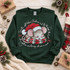 Sleepy gray mouse in a fuzzy white-trimmed Santa hat resting on a red and green plaid pillow DTF transfer with Christmas script text Shown on a Forest crewneck sweatshirt.