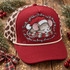 Sleepy gray mouse in a fuzzy white-trimmed Santa hat resting on a red and green plaid pillow DTF transfer with Christmas script text Shown on a garnet red foam front panel with cream rope and leopard print mesh back trucker hat.