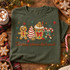 Christmas calories don't count DTF transfer with embroidered-style gingerbread man, striped candy tree, cocoa mug, and candy cane holiday design Shown on a Moss t-shirt.