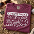 I'd Love To Say It's Just My Face But I Really Just Don't Like You quote DTF transfer with dripping grunge smiley face in white linework on maroon shirt Shown on a Berry t-shirt.