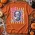 Cutesy horror DTF transfer featuring a spiral-cheeked puppet doll on a tricycle in a pink scalloped frame with bow and stars