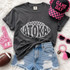 Atoka football outline DTF transfer in white hand-drawn lettering shaped like a football on a dark shirt