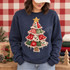 Whimsical patchwork Christmas tree DTF transfer with plaid, snowflake, holly, and heart fabric-print panels, crochet lace trim, gold star topper, and burlap trunk on a green shirt Shown on a Heather Dark Navy crewneck sweatshirt.