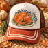 Gobble Til You Wobble Turkey DTF Transfer | Thanksgiving Design, colorful roasted turkey with festive lettering displayed on a fall-themed trucker hat surrounded by pumpkins and autumn leaves