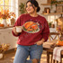 Gobble Til You Wobble Turkey DTF Transfer | Thanksgiving Design, colorful roasted turkey and festive “Gobble Til You Wobble” lettering printed on a red sweatshirt worn by a woman in a cozy Thanksgiving kitchen.