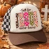 Fall for Jesus He Never Leaves DTF Transfer | Autumn Faith Word Art Design, colorful faith-inspired lettering displayed on a trucker hat against a warm autumn backdrop