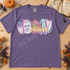 Pastel Michael Myers mask DTF transfer with retro daisies, hearts, coveralls, and butcher knife, lettered with the name Michael in peachy script Shown on a Violet t-shirt.