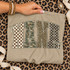 NANA block-letter DTF transfer in checkerboard, camo, leopard, and polka dot patterns with cream ribbon bow accents Shown on a Hemp t-shirt.