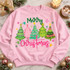 Merry Christmas DTF transfer with five whimsical pastel green, pink, and teal Christmas trees, gold star toppers, and colorful snowflakes above hand-lettered script text Shown on a Light Pink crewneck sweatshirt.