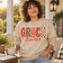 GRACE DTF transfer in mixed red, cream, and leopard print applique-style letters with bows and a red script 2 Cor 12:9 Bible verse underneath Shown on a Sand crewneck sweatshirt.