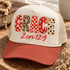 GRACE DTF transfer in mixed red, cream, and leopard print applique-style letters with bows and a red script 2 Cor 12:9 Bible verse underneath Shown on a cream foam front panel with terracotta bill and oatmeal mesh back, cream rope trucker hat.