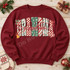 Grandma Christmas DTF transfer with block letters in candy cane, checkerboard, snowflake, and leopard patterns, topped with red cursive script and holly, bow, bell, and candy cane accents Shown on a Garnet crewneck sweatshirt.