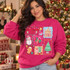 Merry Christmas Y'all DTF transfer with gingerbread house, snowman, Christmas tree, candy cane, gingerbread man, and presents in a pastel doodle-frame grid design Shown on a Heliconia crewneck sweatshirt.