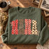 NANA word art DTF transfer with polka dot, leopard print, and checkerboard letters and dainty bow accents in red, cream, and brown Shown on a Military Green crewneck sweatshirt.