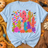 Whimsical folk-art cactus garden DTF transfer with polka dot, heart, and striped cacti, succulents, a striped pumpkin, bright flowers, stars, and black bats Shown on a Ice Blue t-shirt.