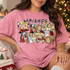 Pop-art Christmas movie mashup DTF transfer with polaroid-style frames featuring classic holiday movie characters, a leg lamp, BB gun, squirrel, and FRIENDS-style lettering Shown on a Blossom t-shirt.
