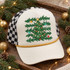 Hand-illustrated Christmas tree DTF transfer with glowing string lights, colorful ornaments, a gold star topper, pine branches, and scattered gold, teal, and red stars Shown on a cream front panel, gold rope, black-and-white checkered mesh back trucker hat.