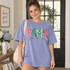 Playful graffiti-style MAMA DTF transfer in alternating pink, teal, and green hand-lettered letters with black outlines and white highlights Shown on a Hydrangea t-shirt.