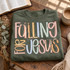 Falling for Jesus DTF transfer in bold hand-lettered multicolor typography with pastel blush, mustard, dusty blue, and sage tones, accented with sage green bow ribbons Shown on a Military Green crewneck sweatshirt.