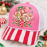 Whimsical Christmas ducks DTF transfer featuring five fluffy ducks in Santa hats and scarves popping out of a checkered gift box with candy canes and holly Shown on a Blossom pink front panel, red-and-white striped bill, soft white mesh back trucker hat.