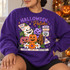 Halloween Patch DTF transfer featuring hand-painted folk-art jack-o'-lantern pumpkins in stars, checks, polka dots, and stripes with wooden sign accents and daisies Shown on a Purple crewneck sweatshirt.