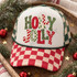 Holly Jolly Christmas DTF transfer in bold bubble letters with mixed leopard print, checkerboard, candy stripe, polka dot, and Christmas tree patterns Shown on a cream front panel with red and cream checkered bill and green and cream checkered mesh back trucker hat.