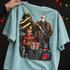 Horror movie villains Christmas DTF transfer with a clawed glove holding a wrapped gift and a hockey-masked figure gripping a bloody machete, framed by a decorated Christmas tree Shown on a Island Reef t-shirt.