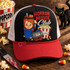 Horror Movie Club DTF transfer with killer doll slushie cup, Good Guys box, bloody knife, popcorn bucket, and bloody Horror Nightmares VHS tape Shown on a black front panel, red bill, white mesh, red rope trucker hat.