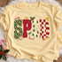 SPED frosted-cookie-lettering DTF transfer with leopard print, checkerboard, and mini Christmas tree patterns surrounded by candy cane, holly, paint palette, book, pencil and ruler doodles Shown on a Butter t-shirt.