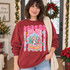 Christmas Town snow globe DTF transfer with pink gingham bow, candy stripes, snowy village scene, red pickup truck, and Est. 1998 banner Shown on a Antique Cherry Red crewneck sweatshirt.