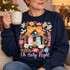 Oh Holy Night nativity DTF transfer with Mary, Joseph, baby Jesus, angel and sheep framed by an orange floral bow, gold star and pastel flowers, pink script lettering below Shown on a Navy crewneck sweatshirt.