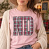 ND collegiate block letters DTF transfer filled with red, green, white, and black tartan plaid pattern and dark charcoal outline on a pink shirt Shown on a Blossom t-shirt.