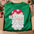 Whimsical Santa face DTF transfer with red polka-dot hat, curly white hair and beard, and pink cheeks in hand-drawn line art style Shown on a Irish Green crewneck sweatshirt.